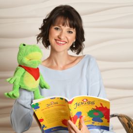 Musikpädagogin mit Handpuppe und Jekiss-Liederbuch – fröhliche Darstellung aus dem musikpädagogischen Unterricht mit Kindern.
