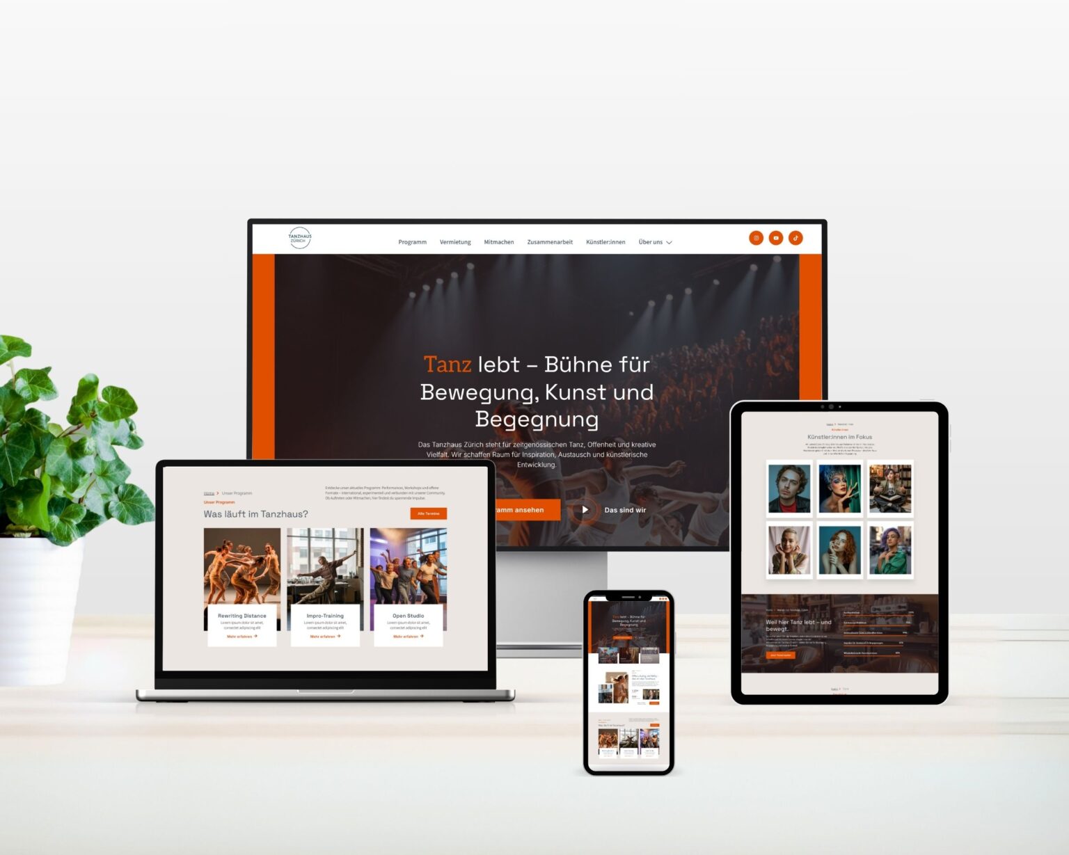 Mehrere Geräte – Laptop, Tablet, Smartphone und Monitor – zeigen die Website des Tanzhaus Zürich in modernem, responsivem Design. Das Layout kombiniert warme Erdtöne mit klarer Typografie und großflächigen Bildern von Tanz, Bewegung und Begegnung. Links steht eine grüne Pflanze auf dem Schreibtisch, was der Szene eine frische, harmonische Note verleiht.